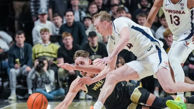 Andrew Rohde and Andrew Carr dive for a loose ball during the Virginia men's basketball game against Wake Forest at LJVM Coliseum.